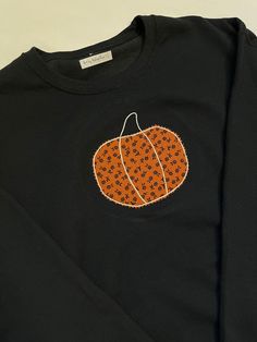 This charcoal sweatshirt is a unisex with a hand embroidered pumpkin in fabric applique on the front chest area. Orange with black floral pumpkin. Black Cotton Sweater With Embroidered Graphics, Black Cotton Halloween Sweater, Black Embroidered Cotton Sweater, Black Cotton Embroidered Sweater, Black Embroidered Tops For Halloween, Black Tops With Embroidered Graphics For Fall, Black Embroidered Sweater For Fall, Black Cotton Sweatshirt For Fall, Black Embroidered Tops For Fall