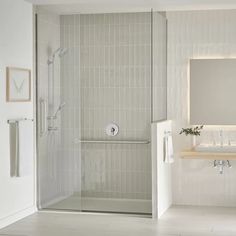 a bathroom with a walk in shower next to a white sink and mirror on the wall