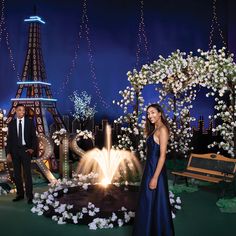 a man and woman standing in front of the eiffel tower with flowers around them