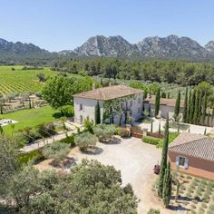 an aerial view of a large house surrounded by trees and bushes with mountains in the background