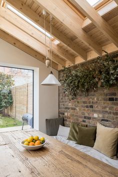 a bowl of fruit sitting on top of a wooden table next to a brick wall