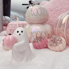 some fake ghost figurines sitting on top of a white bed next to pink pillows