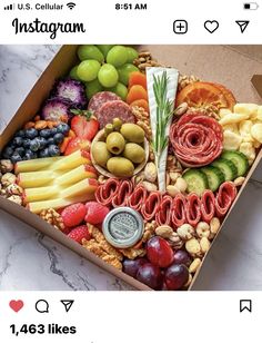 a box filled with assorted fruit and nuts on top of a marble countertop