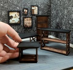 a hand is pointing at some miniature furniture