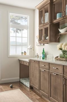 a kitchen with wooden cabinets and white flowers in vases on the window sill