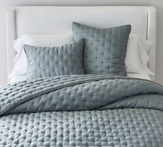 a bed with blue comforters and pillows on it