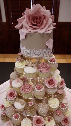 a three tiered cake with cupcakes on the bottom and pink roses on top