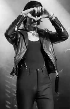 a woman standing on top of a stage holding her hands up to her face and covering her eyes