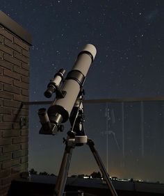 a telescope on a tripod in front of a night sky