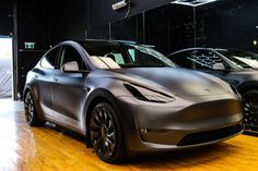 two electric cars parked in front of each other on a hard wood floored area