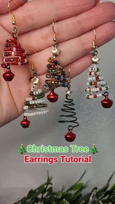 the christmas tree earrings are being held in someone's hand with beads on it