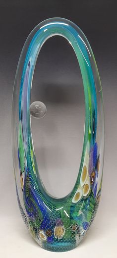 an artistic glass sculpture is displayed on a white surface with blue, green and yellow colors