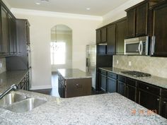 a kitchen with granite counter tops and black cabinets