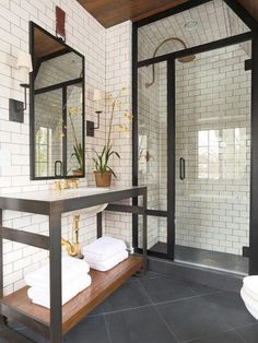 a bathroom with black and white tiled walls, two sinks and mirrors on the wall