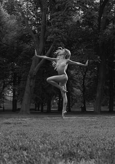 a naked woman is in the middle of a field with trees and grass behind her