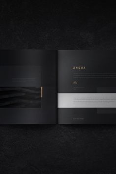 an open book with black pages and gold foil on the cover, sitting on a dark surface