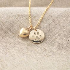 two gold necklaces with paw prints and heart on the front, one has a dog's paw print