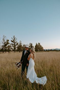 a bride and groom walking through tall grass