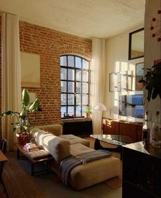 a living room filled with furniture and a brick wall in front of a large window