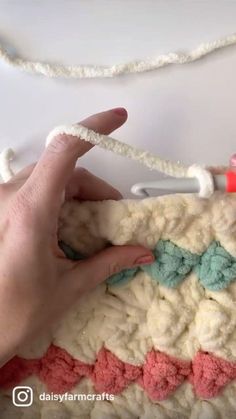 someone is crocheting something with yarn on the edge of a piece of cloth