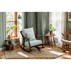 a rocking chair in a living room with green walls and wooden flooring next to a window