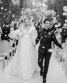 a man and woman walking down a aisle with confetti thrown in the air