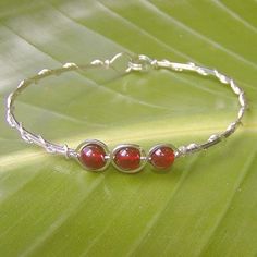 Three elegant, rich orange-red 6mm genuine carnelian beads, set in a sterling silver wire bracelet. The delicate outline-and-overwrap design is a sleek new level of style either by itself or stacked with other bangles! Perfect for wearing everyday with all the earthtones in your closet! The built-in hook-and-eye style clasp is easy to get on and off. Carnelian Bracelet Jewelry Gift, Carnelian Bangle Bracelet Gift, Handmade Adjustable Red Sterling Silver Bracelet, Adjustable Carnelian Beaded Jewelry, Adjustable Carnelian Gemstone Jewelry, Silver Carnelian Jewelry With Gemstone Beads, Adjustable Nickel Free Carnelian Jewelry, Adjustable Nickel-free Carnelian Jewelry, Silver Carnelian Gemstone Bracelets