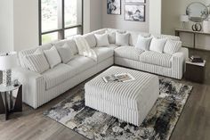 a large white sectional couch sitting on top of a wooden floor next to a window