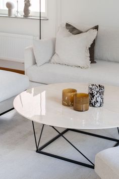 a living room with two candles on the coffee table and white sofas in the background