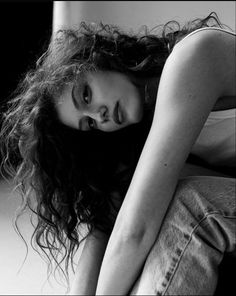 a black and white photo of a woman sitting on the floor with her head in her hands