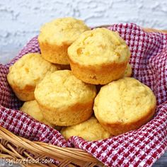 a basket filled with muffins on top of a red and white checkered cloth