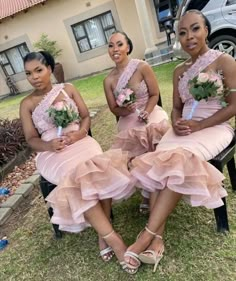 three bridesmaids in pink dresses sitting on a chair outside the house with their bouquets