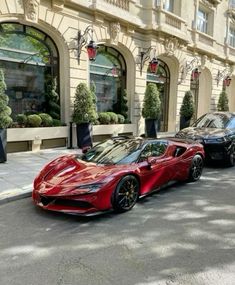 two red sports cars parked on the side of the road in front of a building