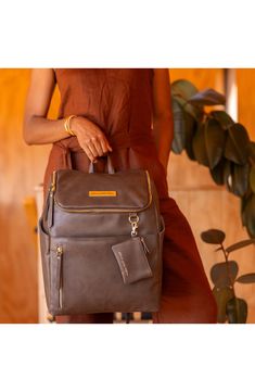 a woman sitting on a chair with a brown bag in front of her and the bottom part of her handbag