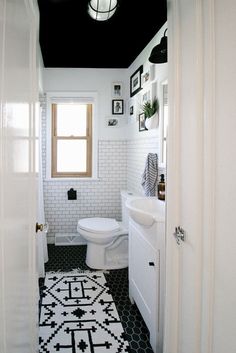 a white toilet sitting next to a sink in a bathroom under a black and white ceiling