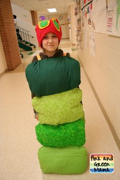 a young boy is dressed up as a stack of pillows in the hallway for halloween