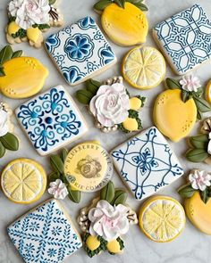 decorated cookies with lemons and flowers on a marble countertop, next to blue and white tiles