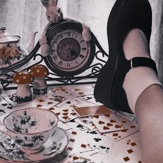 a woman sitting at a table with a clock and tea set on top of it