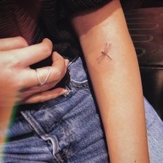 a woman's arm with a small dragonfly tattoo on the left side of her arm