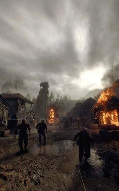 some people are walking around in the mud near fire hydrants and small buildings on a cloudy day