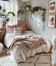 a bedroom with plants on the wall and a bed covered in white sheets, pillows and blankets