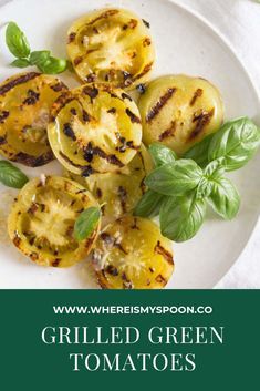 grilled green tomatoes on a white plate with basil sprigs and text overlay