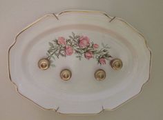 a white plate with pink flowers painted on the side and gold trimming around it