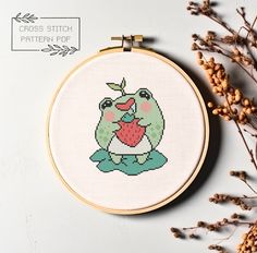 a cross stitch pattern with a frog holding a heart