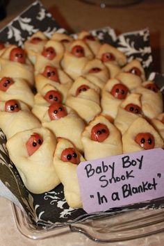 a tray filled with pigs in a blanket on top of a table next to a sign that says baby boy stock in a blanket