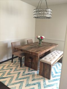 a dining room table with two benches and a chandelier