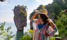 a woman in a hat looking out at the ocean