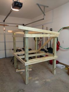 an unfinished bed frame in a garage with tools hanging on the wall and overhead lighting