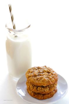 two cookies on a plate next to a glass of milk