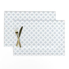 two place mats with forks and spoons on them against a white wallpaper background